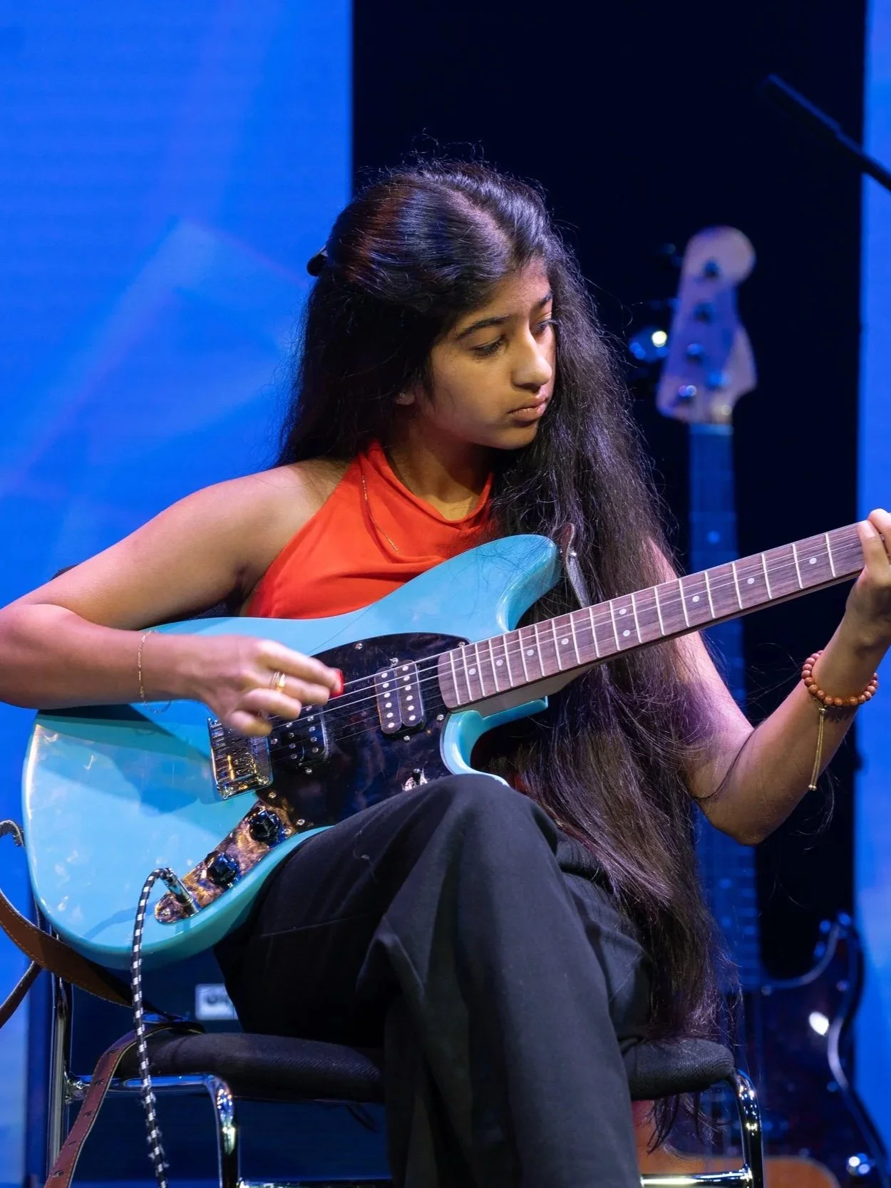 A young girl performing and playing a blue guitar