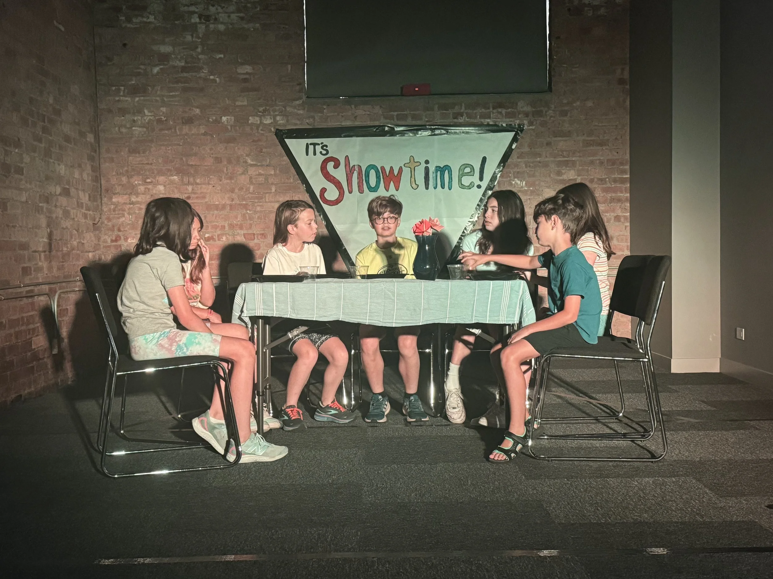 Campers are sitting a table performing a scene
