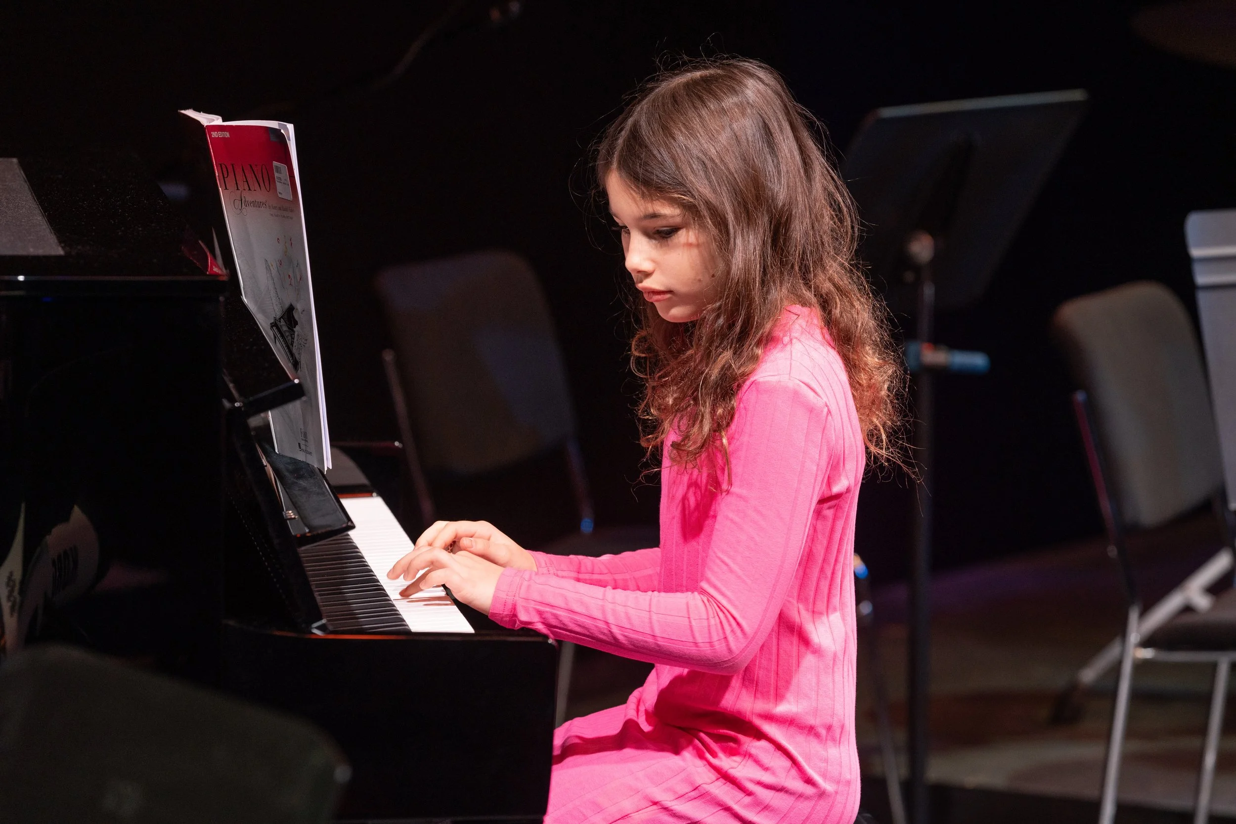 Young girl in pink playing the piano, very focussed