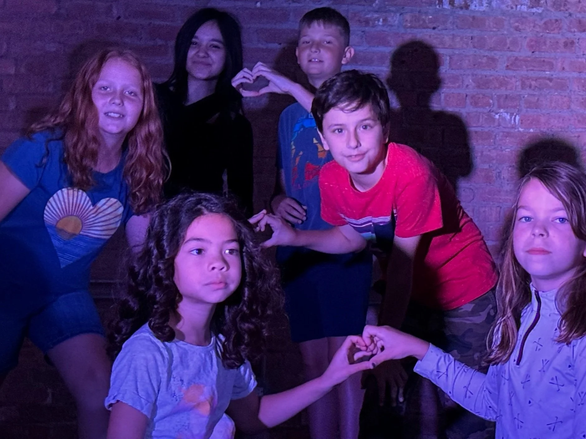 Students create a heart with their hands during a performance