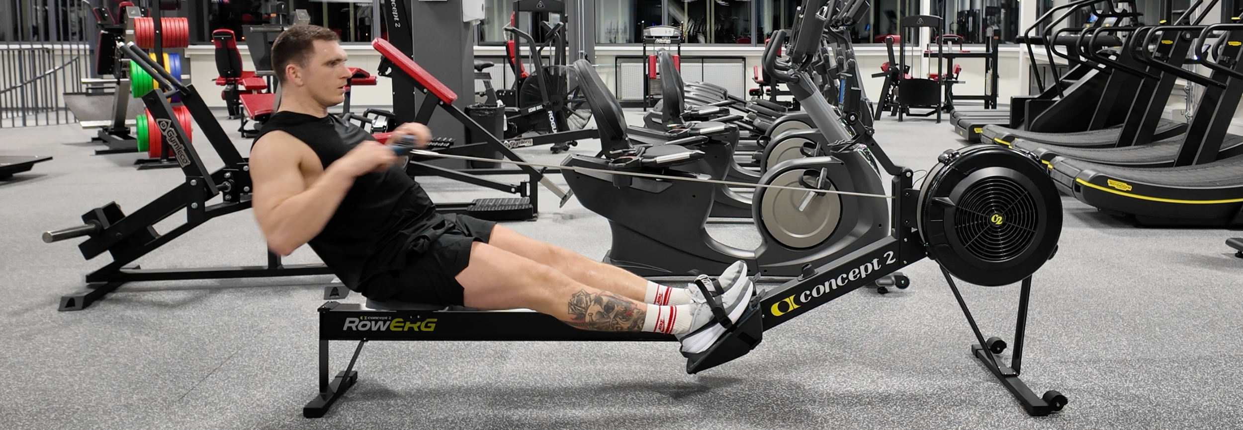 hyrox athlete using concept2 rowing machine in 24-7 fitness keila gym