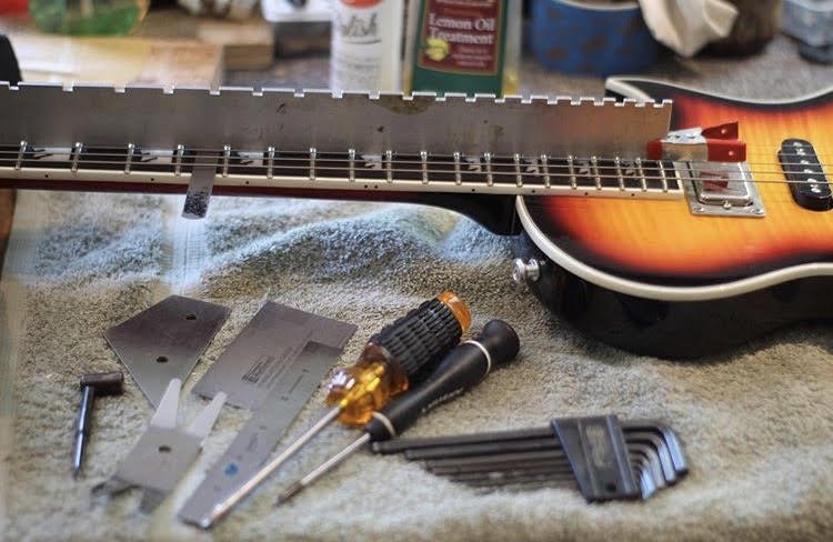 Electric guitar maintenance setup with precision tools.