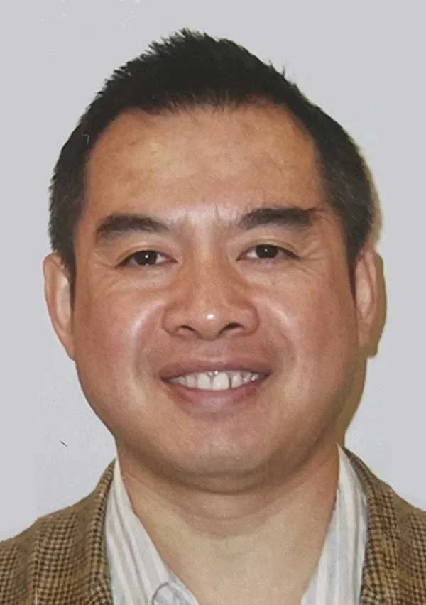 Smiling person portrait wearing a brown jacket and striped shirt