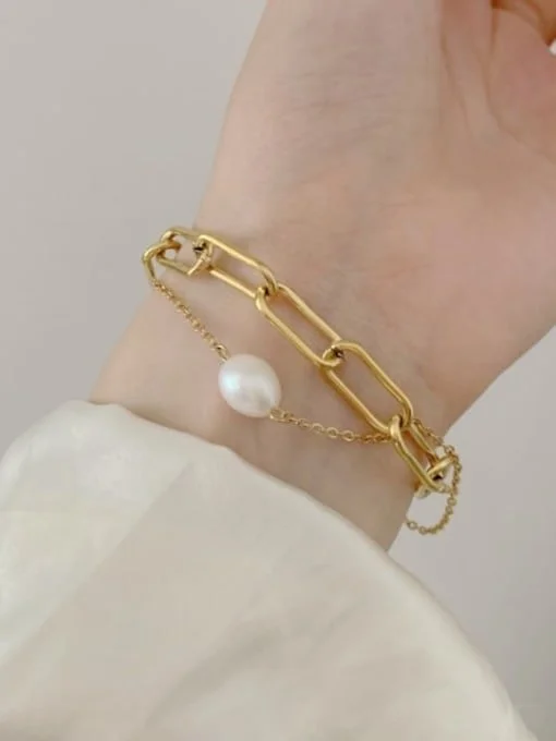Pulsera dorada con cadenas y un colgante de perla.