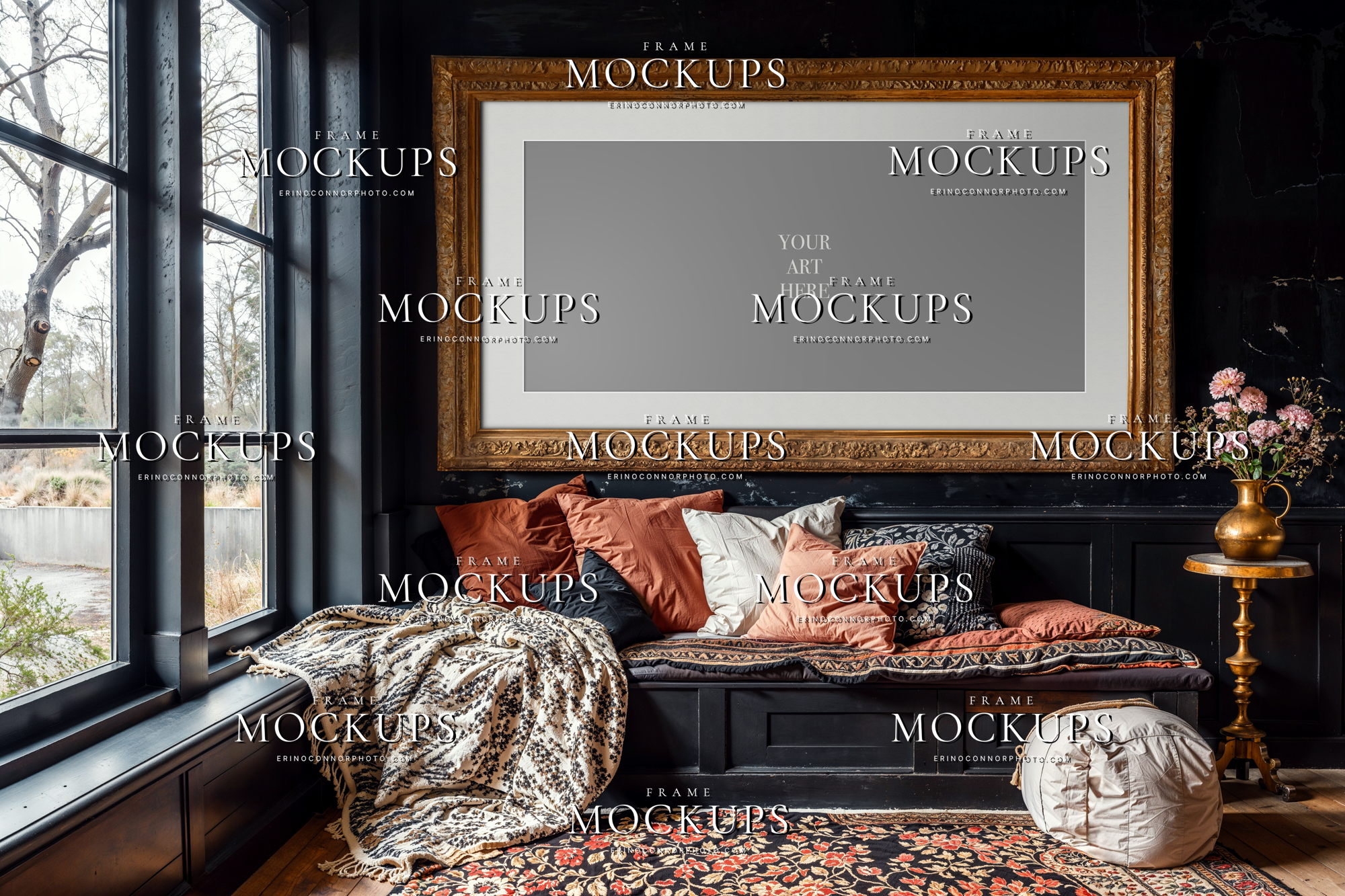 Boho cottagecore frame mockup with a blank horizontal gilded frame above a window bench, black paneled walls, floral rug, and cozy layered pillows.
