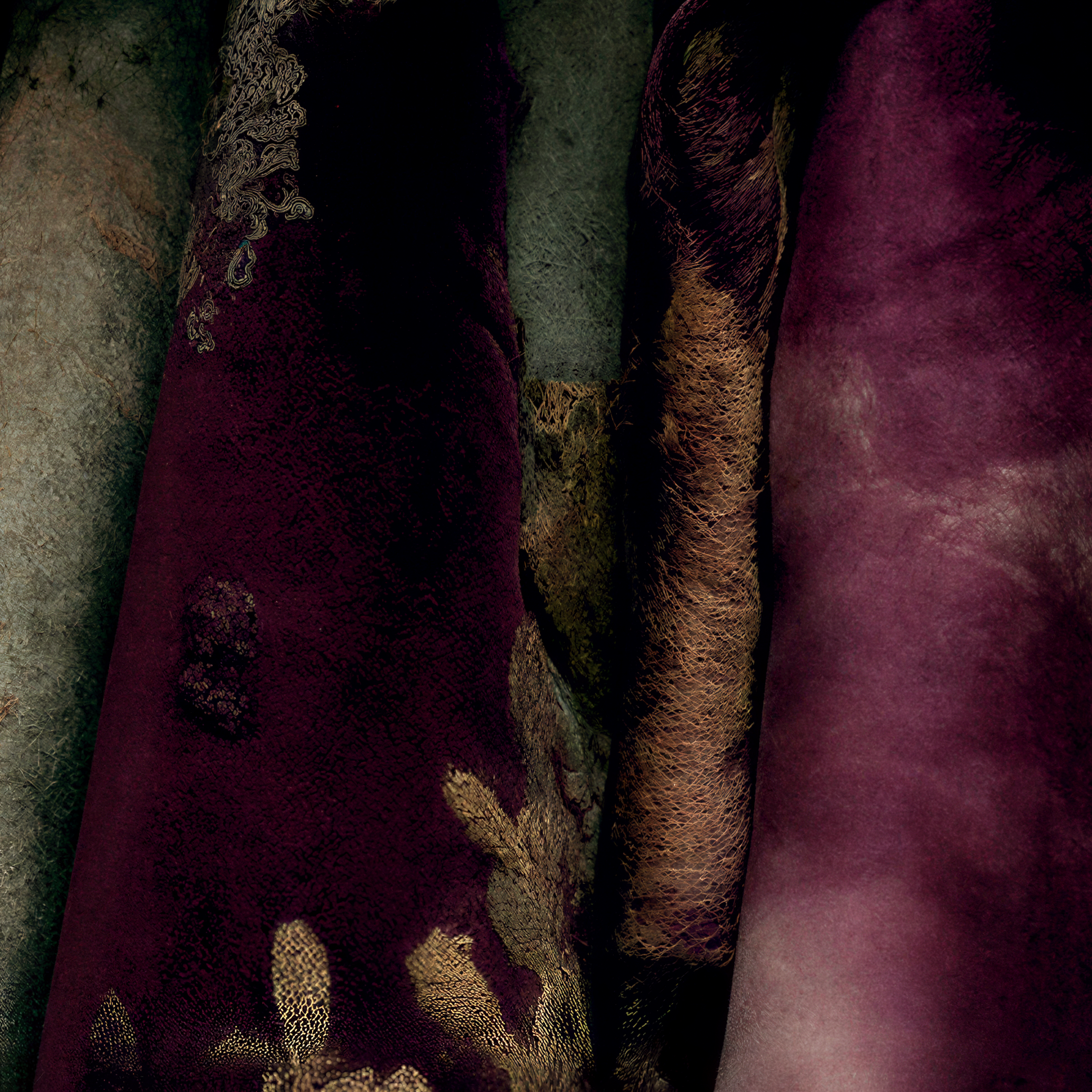 Close textile detail showing plum, muted green-gray, cream and warm brown areas within Cressida's patterned garment.
