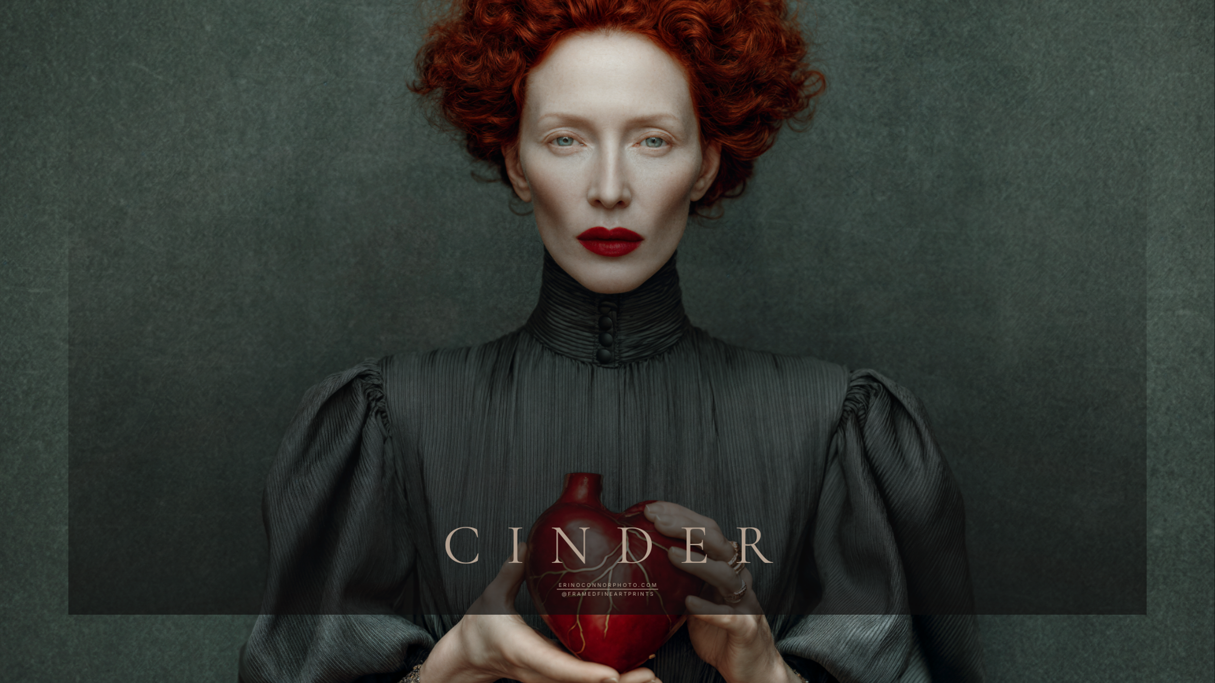 Cinder holding a red symbolic heart with visible gold repairs against her structured gray garment.