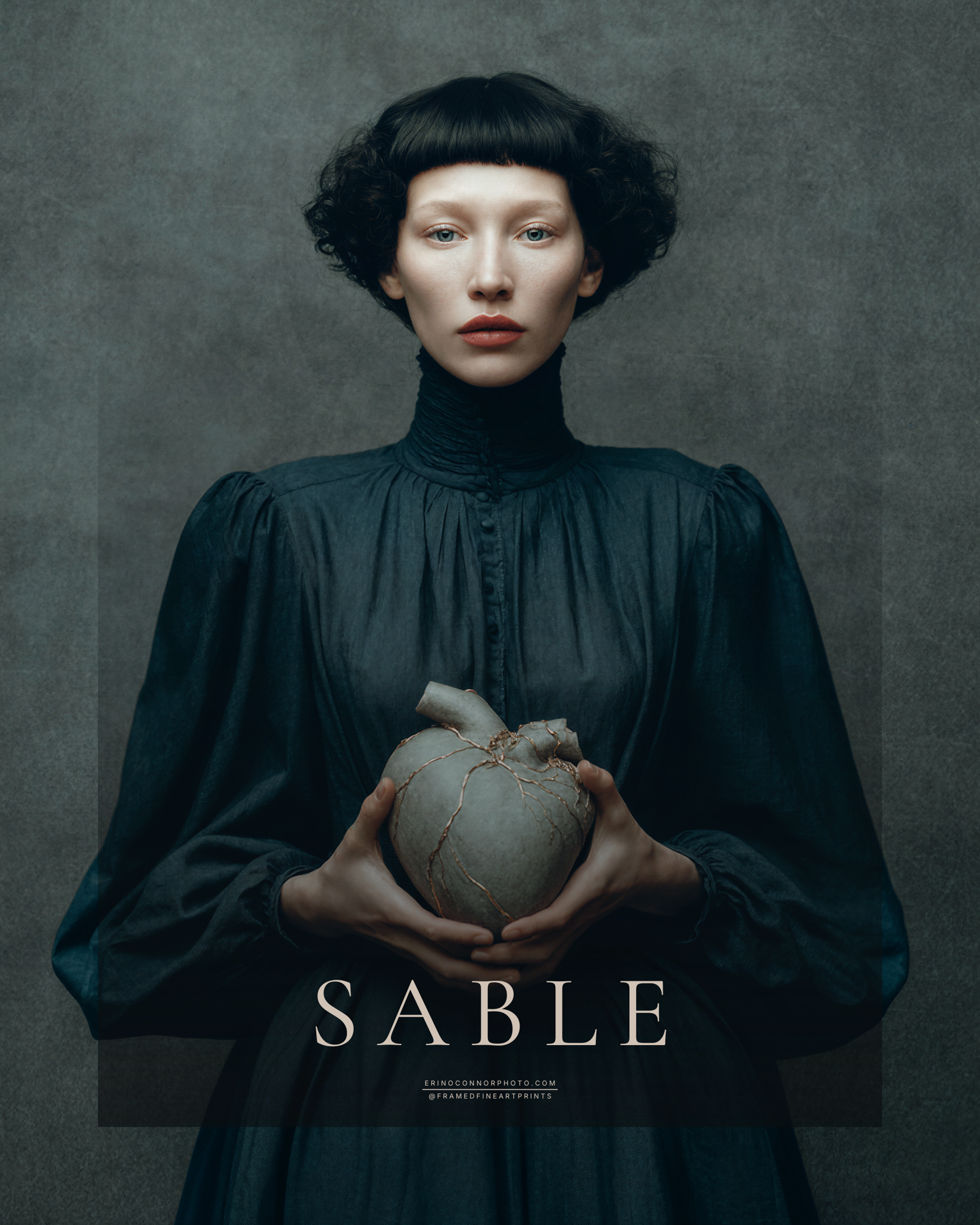 Sable fine art portrait of a dark-haired woman in a blue-black dress holding a pale symbolic heart repaired with metallic lines.