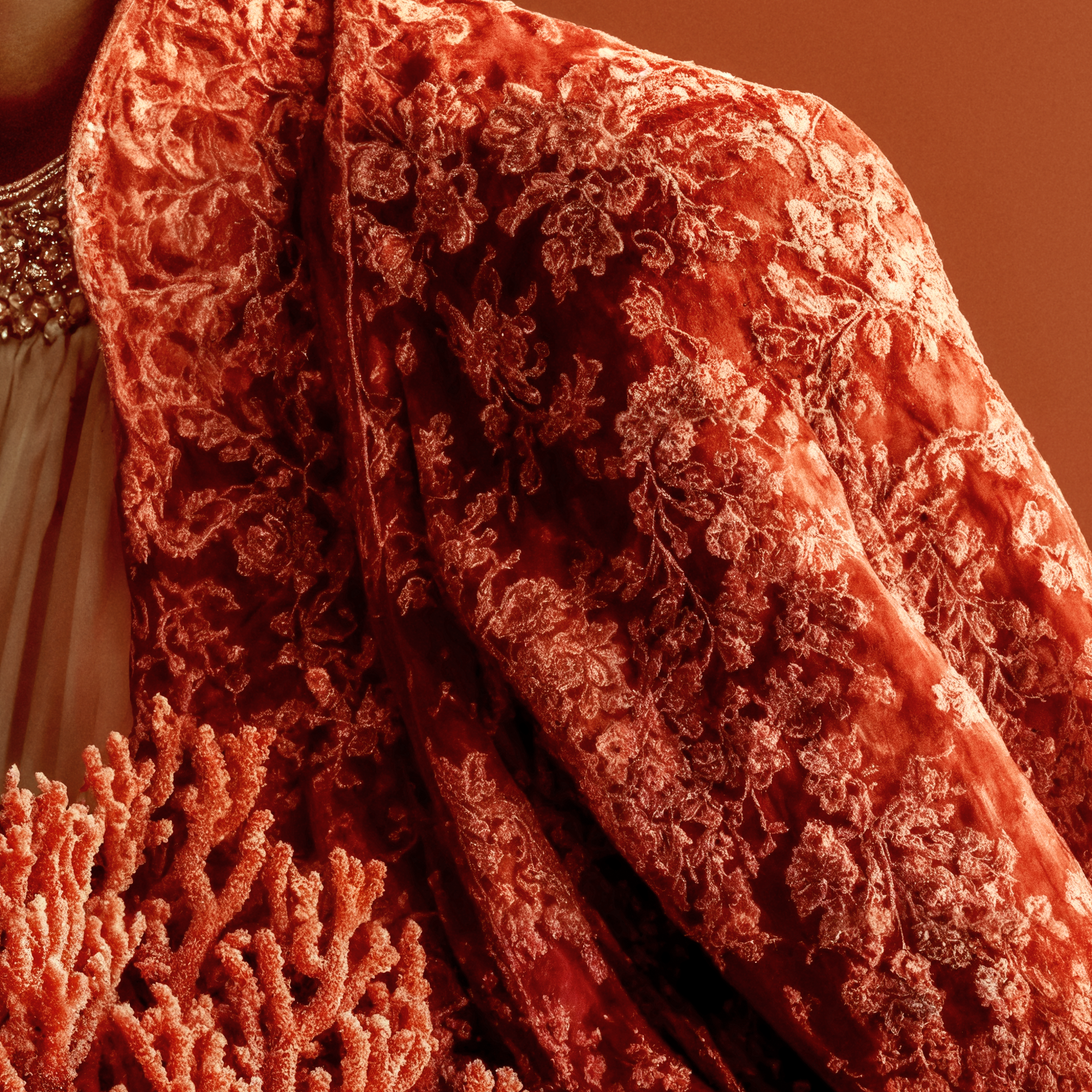 Close detail of the richly patterned red brocade garment worn by Kavya.
