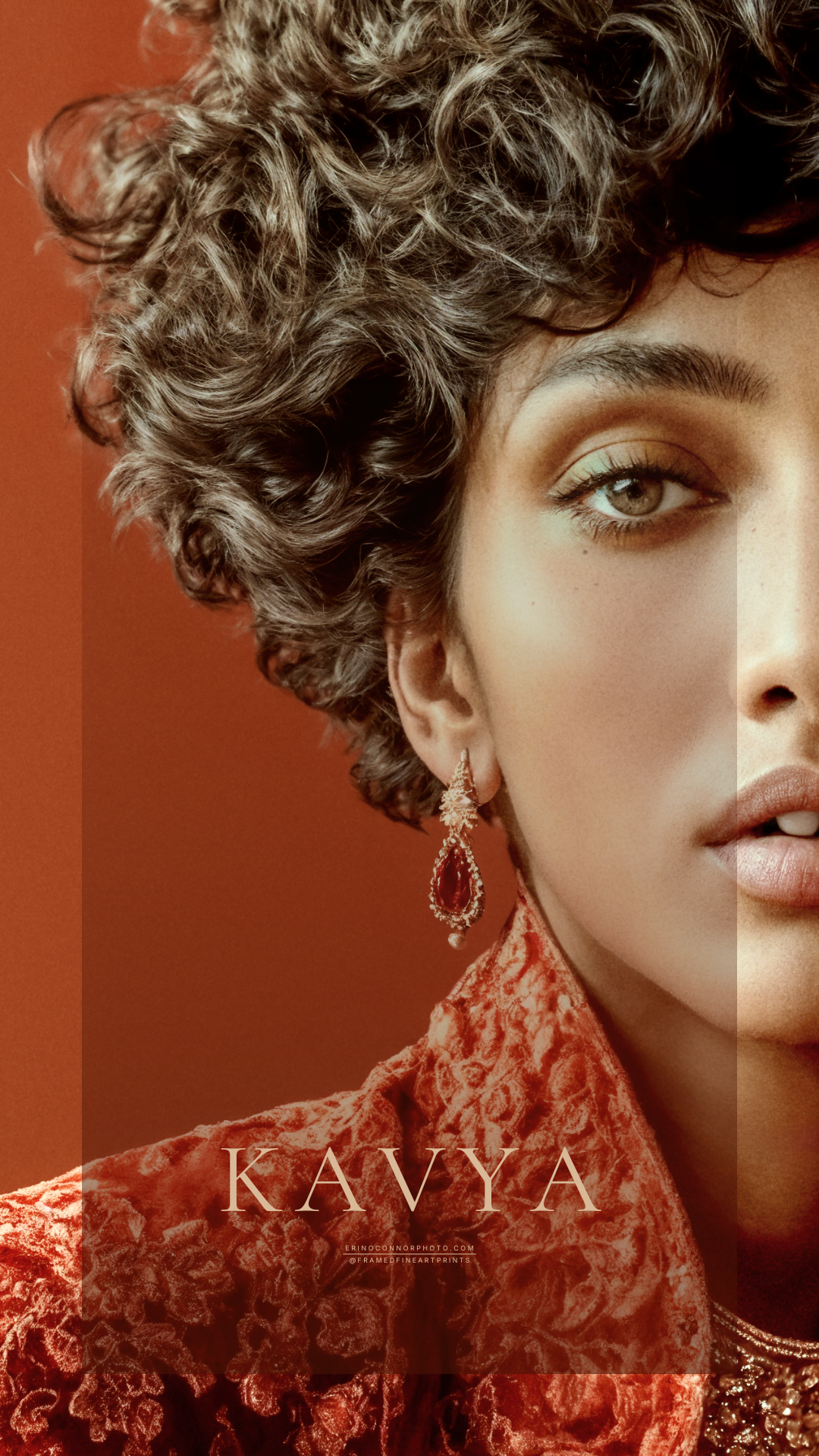 Close portrait of Kavya with dark curled hair, a red drop earring and an ornate red brocade collar.
