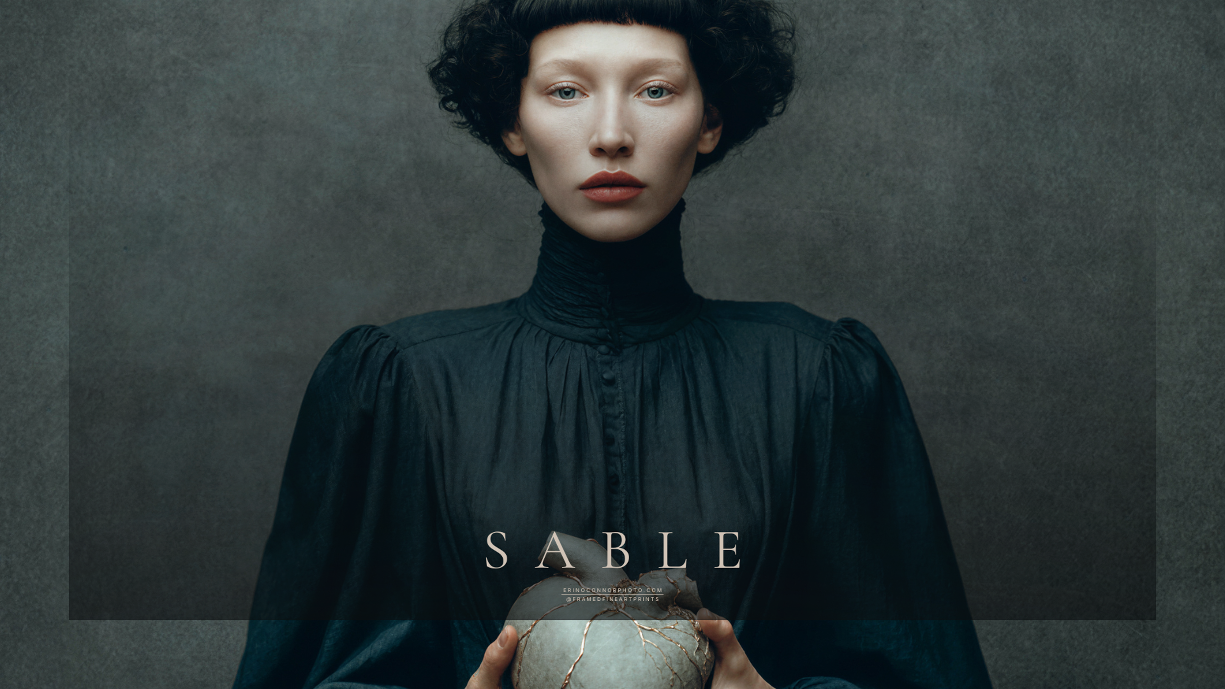 Sable holding a pale repaired heart with visible metallic kintsugi seams against her dark blue-black garment.