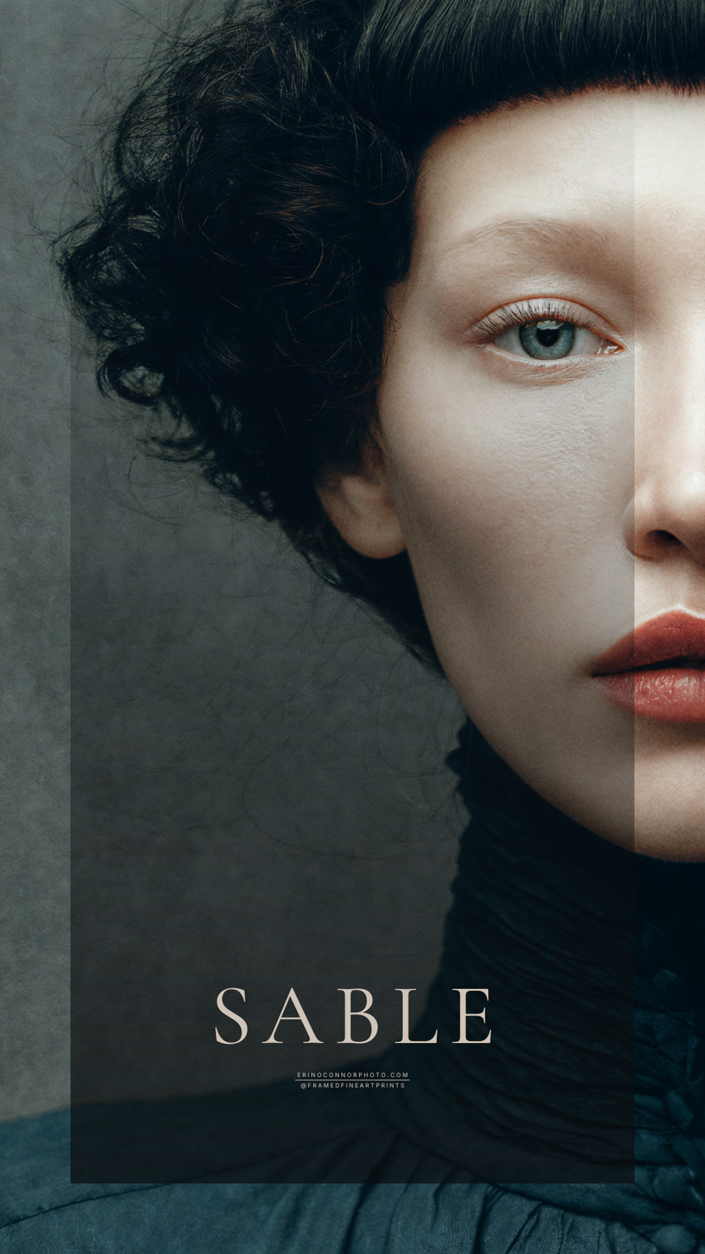 Close portrait of Sable with dark sculpted hair, pale skin and blue eyes against a textured gray background.