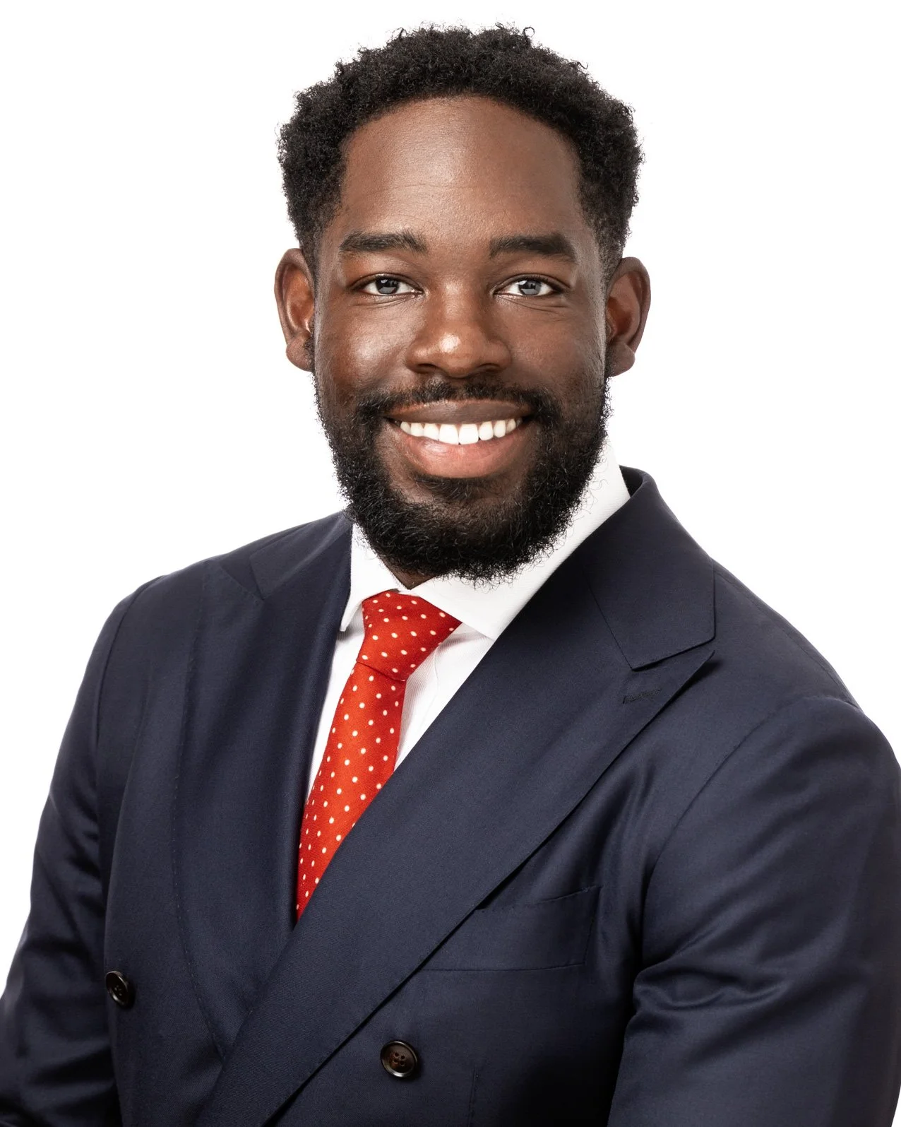 Executive headshot of a smiling man wearing a navy suit and red tie against a clean white background.