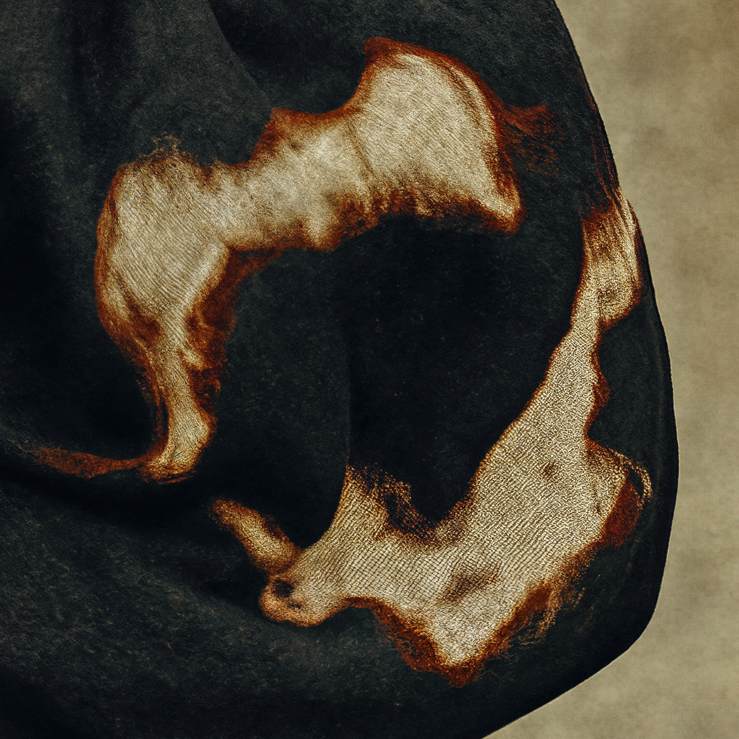 Close detail of the intentional warm ivory and rust abstract pattern across the black sleeve of Arden's garment.