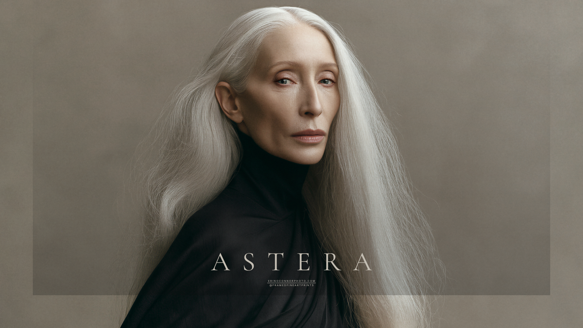 Astera standing in black with long silver hair while holding a pale portrait likeness against a warm neutral background.