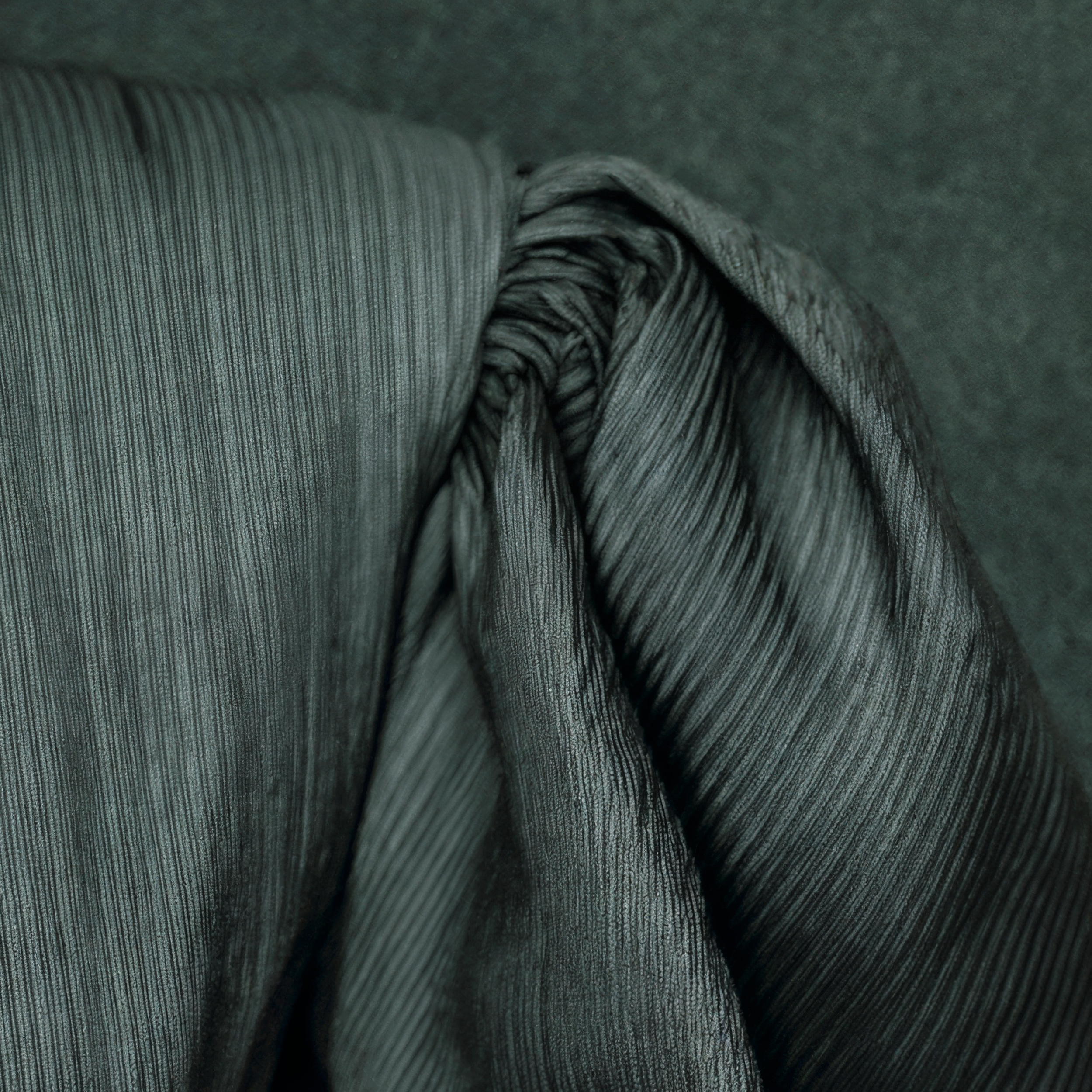 Close detail of the pleated charcoal gray high-neck garment and textured sleeve worn by Cinder.