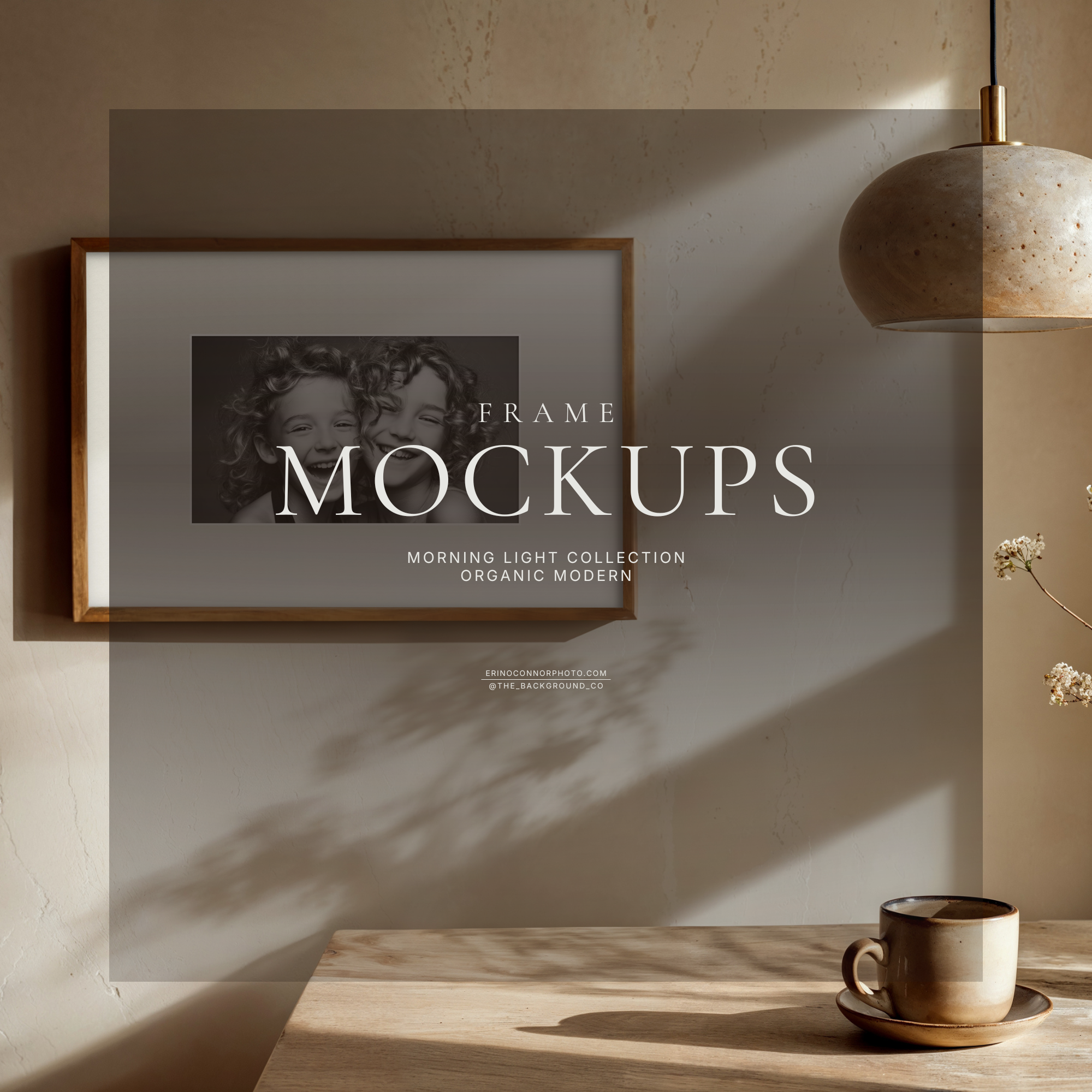 Organic modern wall art mockup with plaster texture, wood table, ceramic vase and coffee cup, stone pendant light, and a horizontal wood frame with wide white matte in morning light.