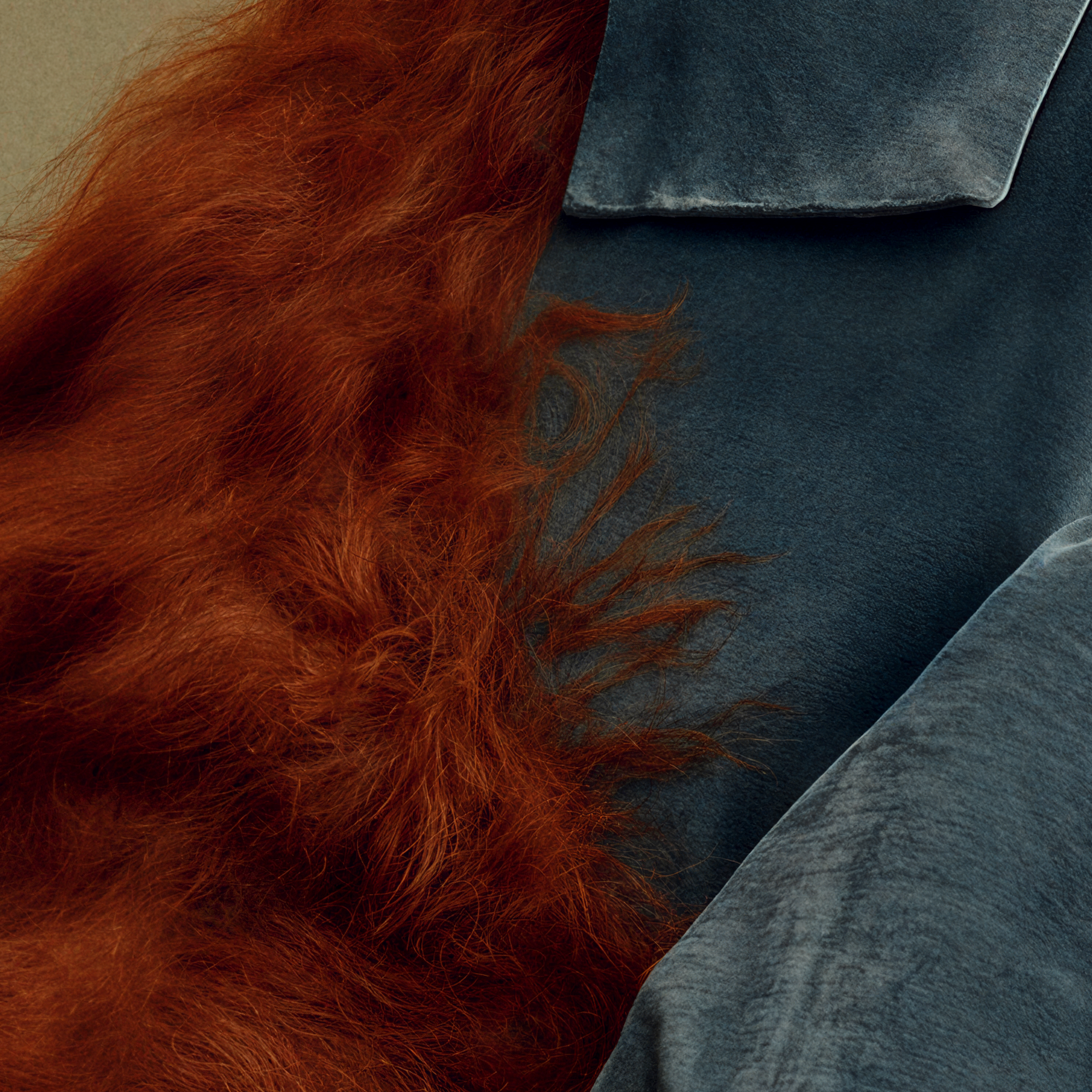 Close-up of rust-colored fibrous textile layered over Ottilie’s deep teal garment.
