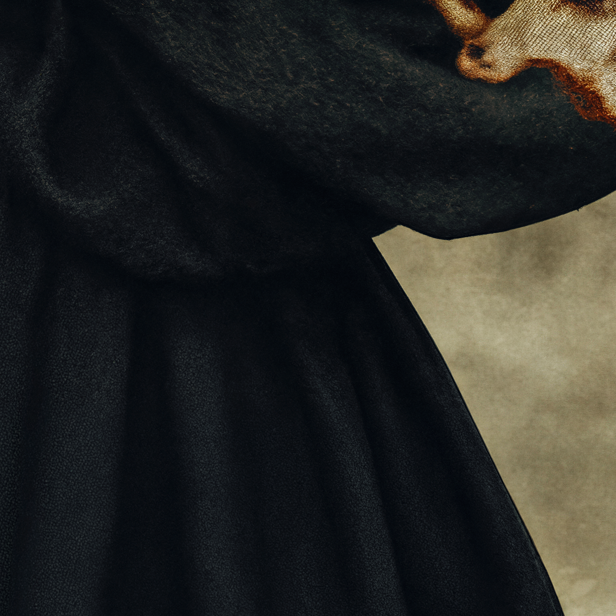 Close detail of Arden's voluminous matte black garment and the transition into its warm abstract sleeve pattern.