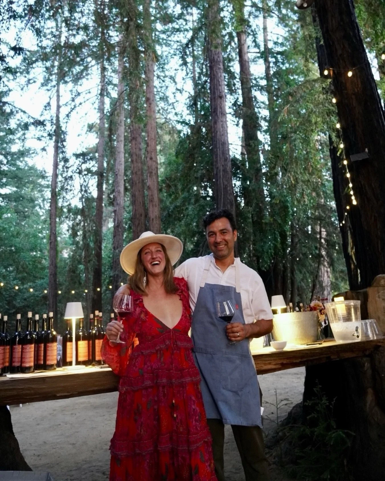 Candlelit table set beneath redwoods at a Colectivo Felix harvest dinner in Los Gatos