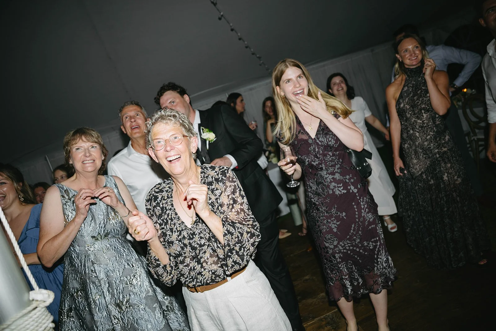 Group of people at a celebration or wedding, smiling and enjoying the moment indoors.