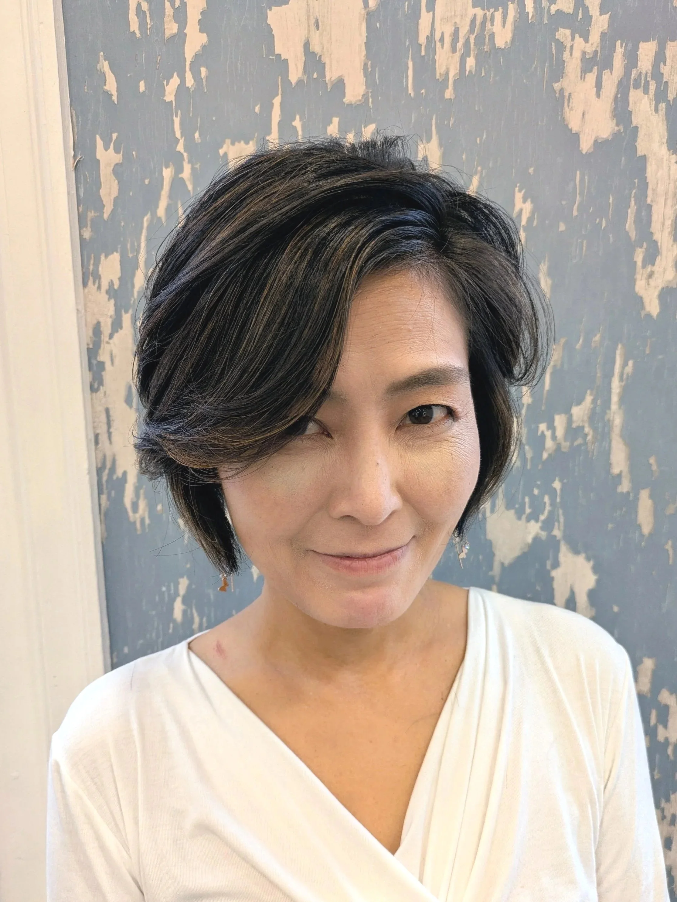 Close-up of pink and white dahlias and lilies in a bouquet against a plain background.