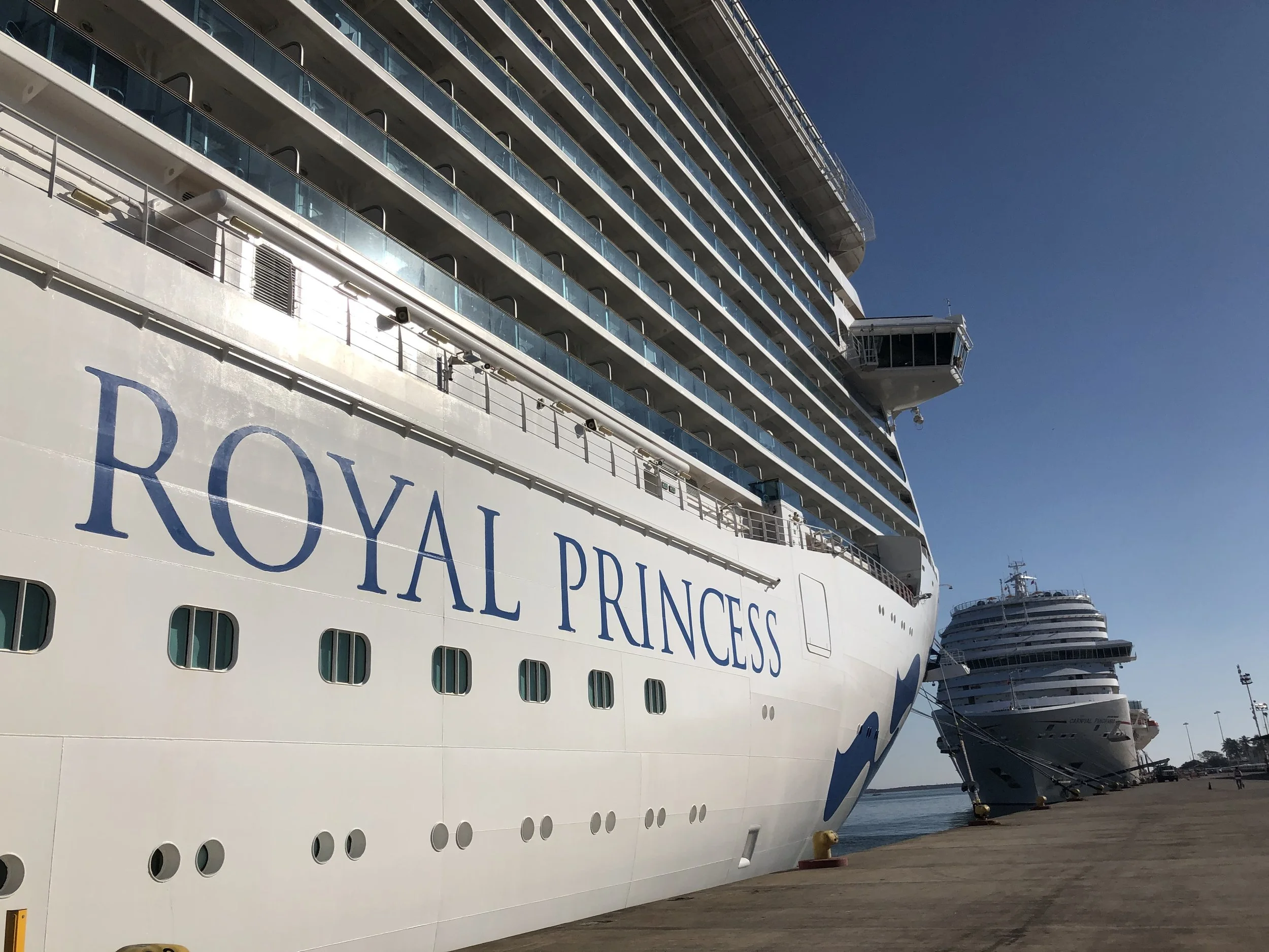 The Royal Princess name painted on the ship's hull while the ship is docked beside another vessel.
