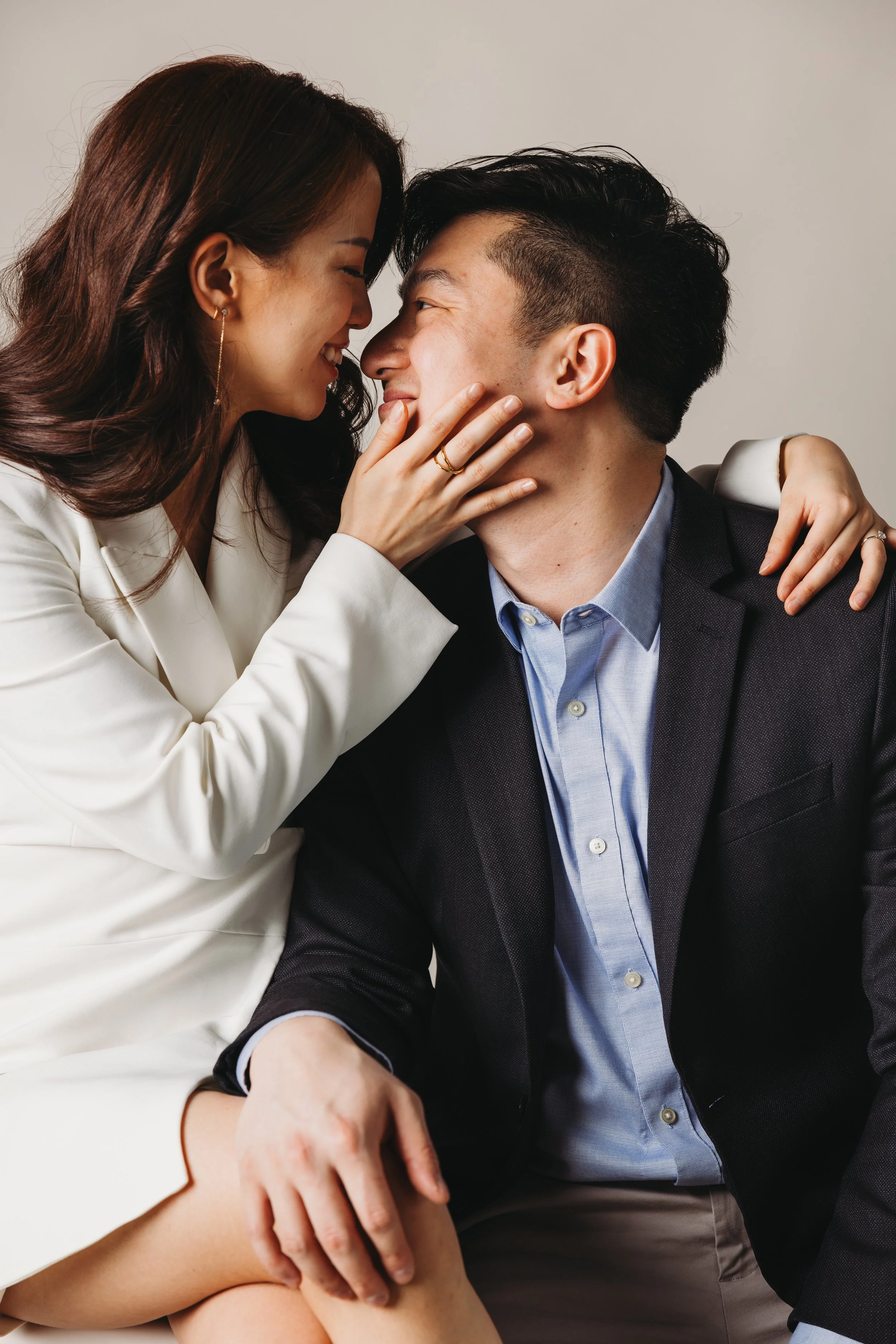 A smiling couple touching foreheads, with the woman touching the man's face and her arm around his shoulder, close together