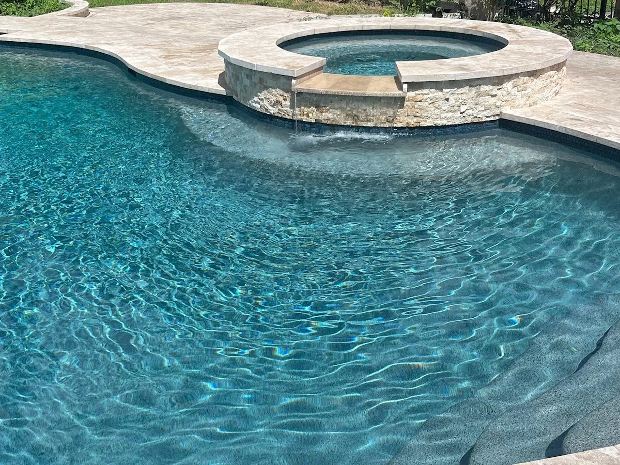 Travertine coping and a stacked stone spa spillover
