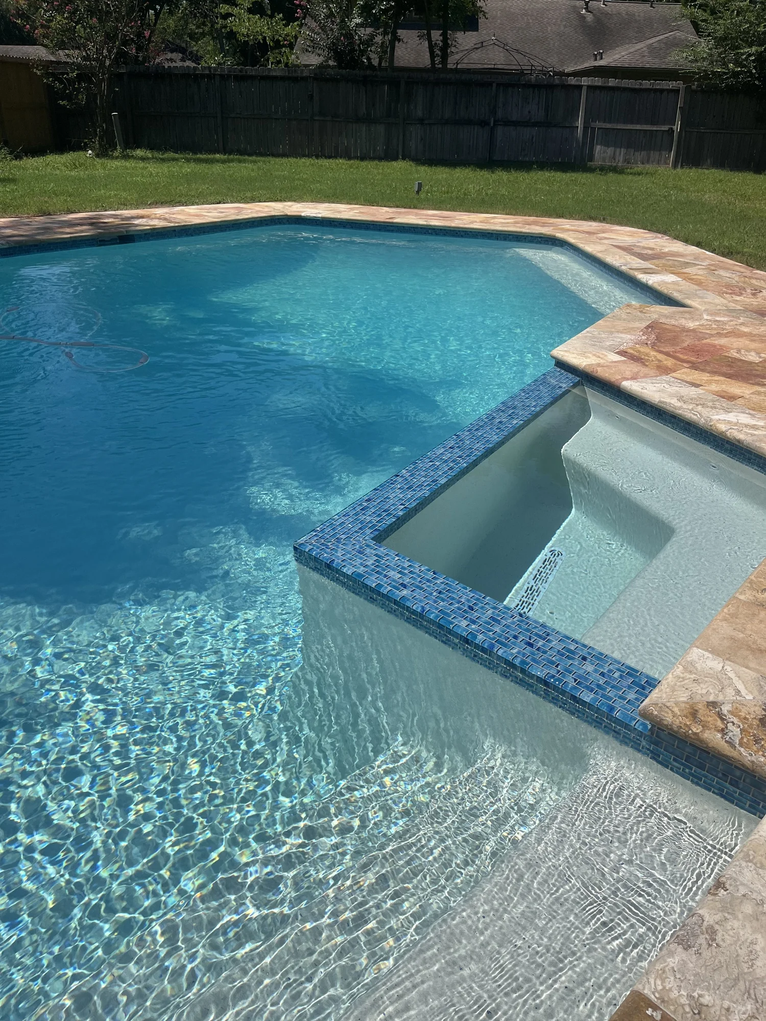 Finished pool renovation with glass tile spa and travertine coping