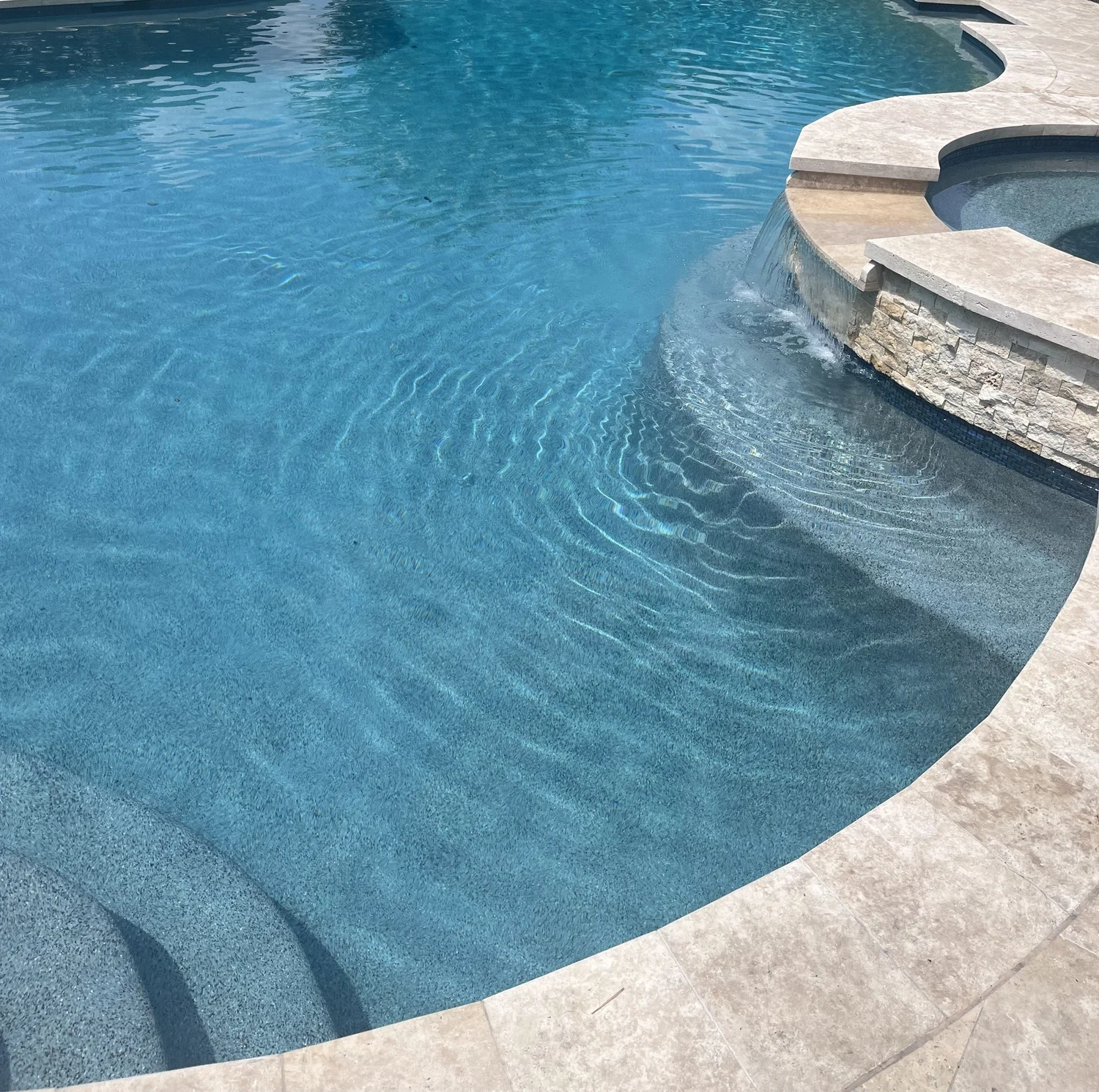 Clean pool with pebble finish and spa spillover