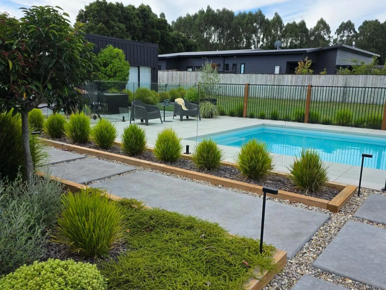 Soft low planting surrounds a turquoise swimming pool