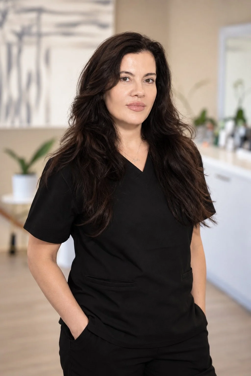 Black and white portrait of a woman with long dark hair wearing a black shirt, looking to the side against a plain background.