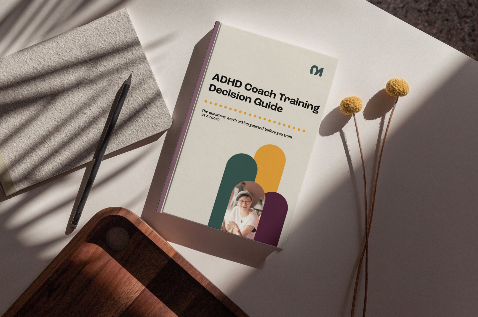 Image of a book titled ADHD Coach Training Decision Guide on a white table next to paper and a pencil