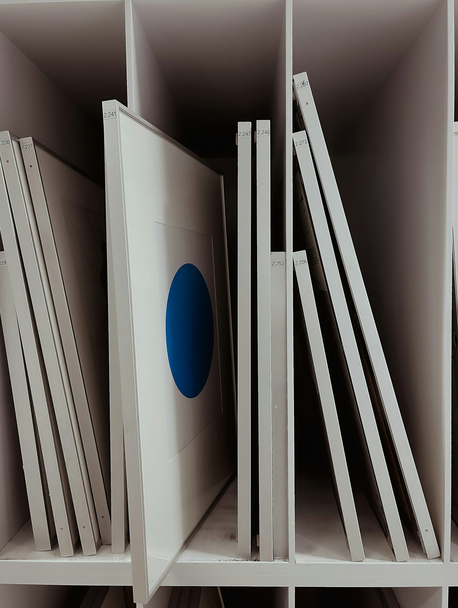 Display of white Ikea shelving units with various-sized shelves and a blue circle on one of the shelves.