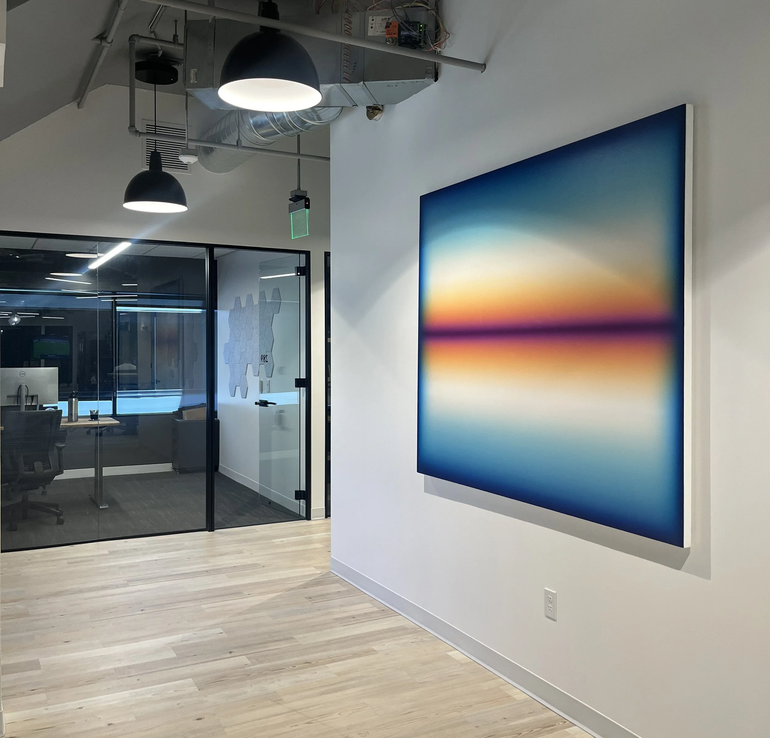 Contemporary commercial office space with a large luminous sunset painting by Patrick DeAngelis, illustrating art consulting and placement services for commercial spaces by Page Art Projects.