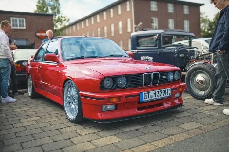 Roter BMW E30 kombiniert mit anderen Oldtimern bei einem Auto-Treffen