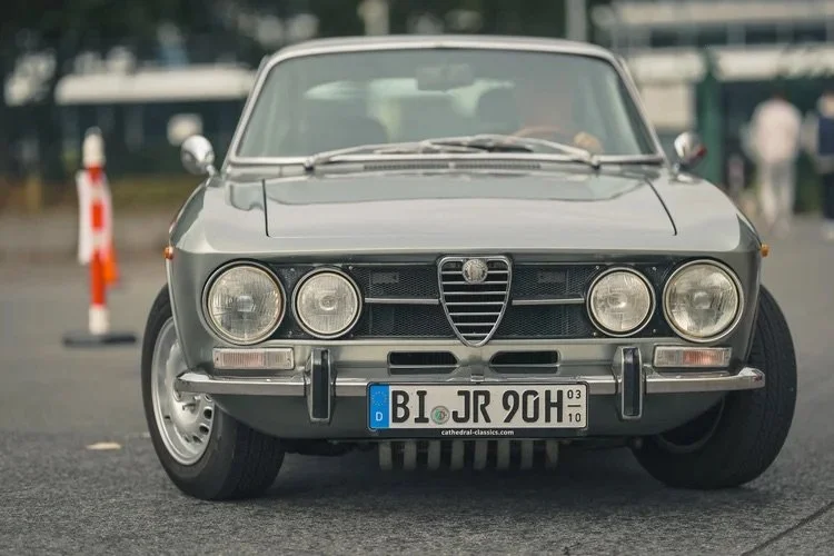Vordere Ansicht eines klassischen grauen Alfa Romeo Autos mit deutschem Nummernschild auf einer Straße