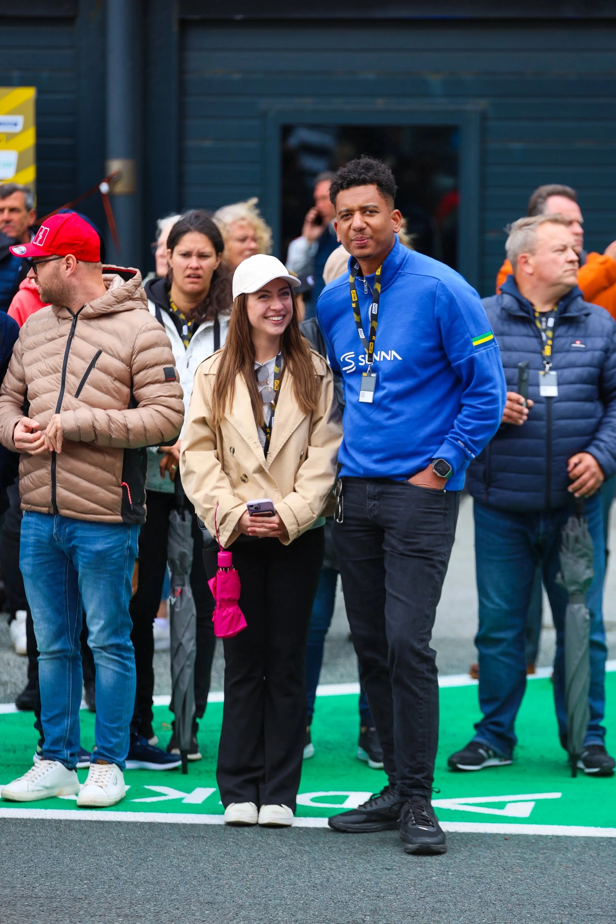 Menschenmenge bei einem Outdoor-Event, zwei Personen im Vordergrund, eine Frau mit weißer Mütze und beige Jacke, ein Mann in blauer Jacke, im Hintergrund weitere Besucher