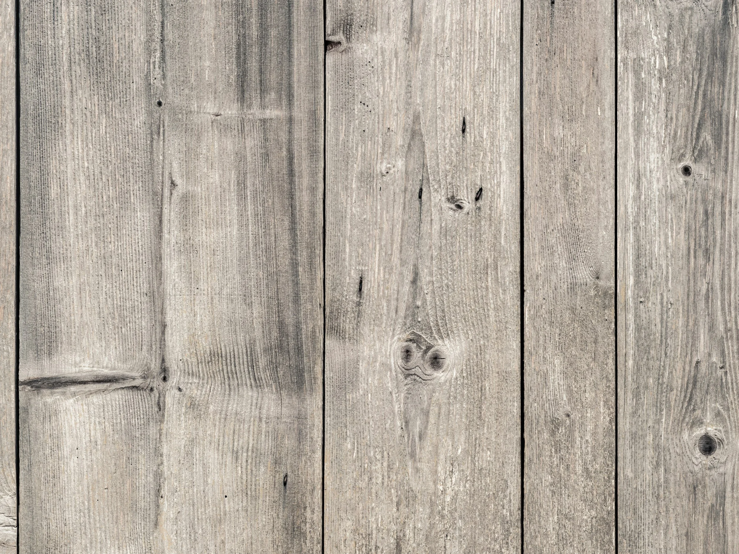 A close-up of weathered wooden planks showing natural grain, knots, and nail holes.