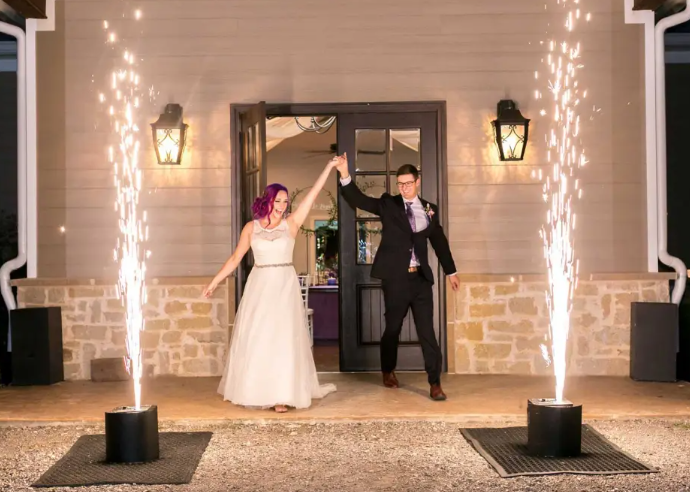 A bride and groom sharing a dance at their wedding reception, in a decorated banquet hall with string lights and guests seated at tables.