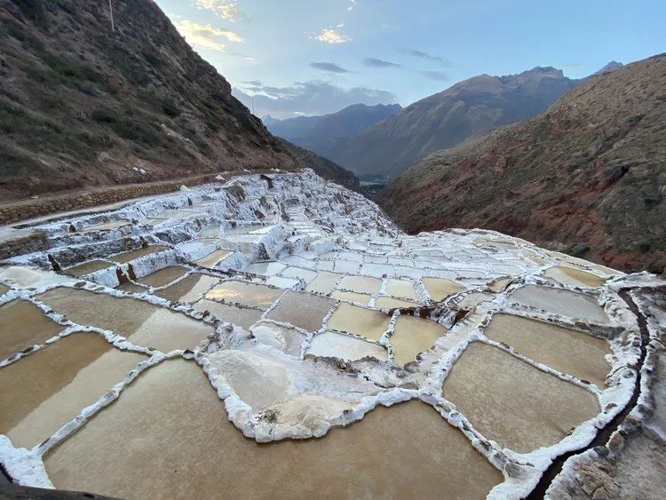 Salt terraces in a mountainous landscape with mountain ranges in the background.