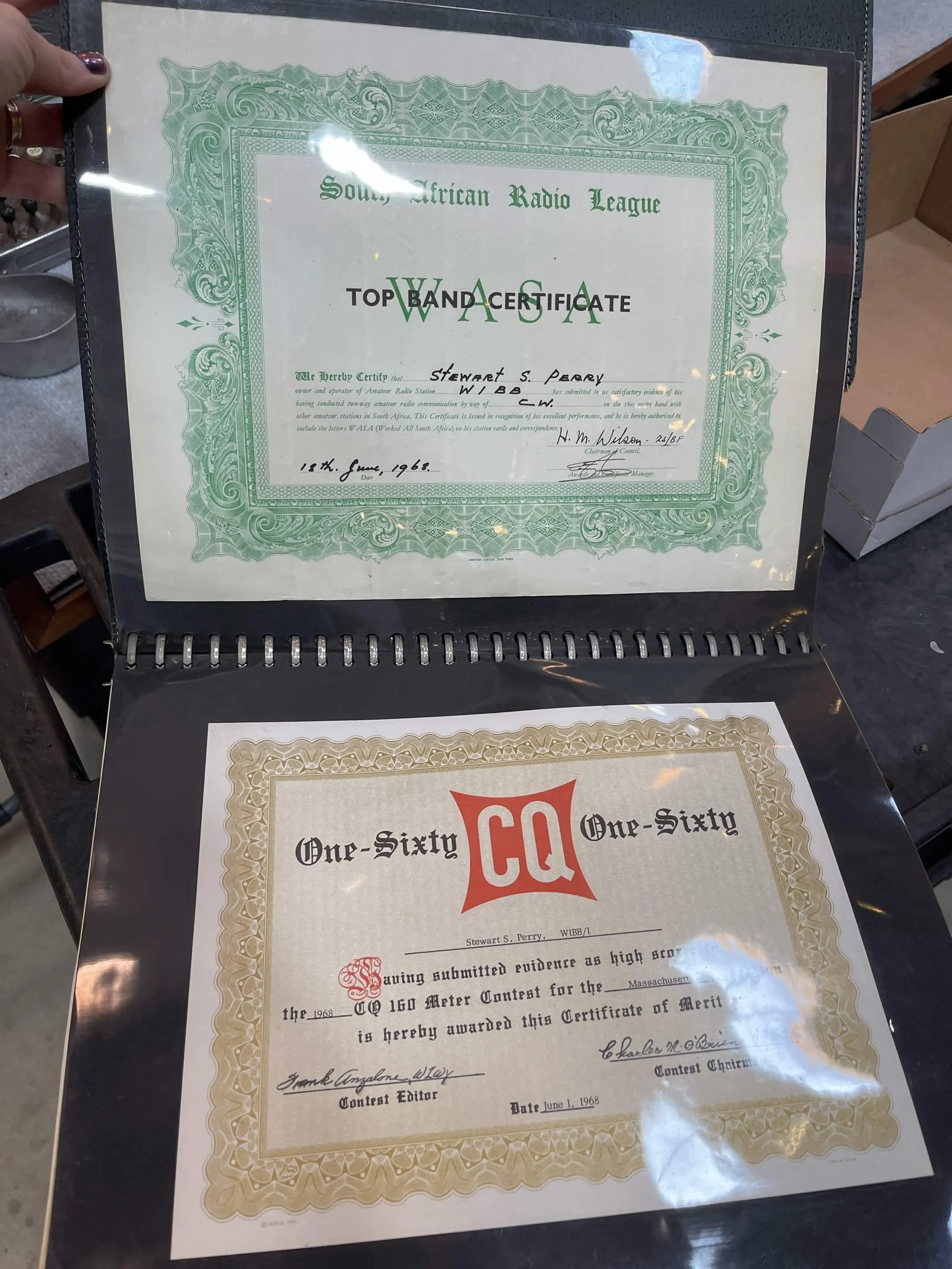A framed certificate from the South African Radio League awarded to Stewart S. Perry on June 18, 1968, with green ornate border and black and red text, seen through a glass covering.
