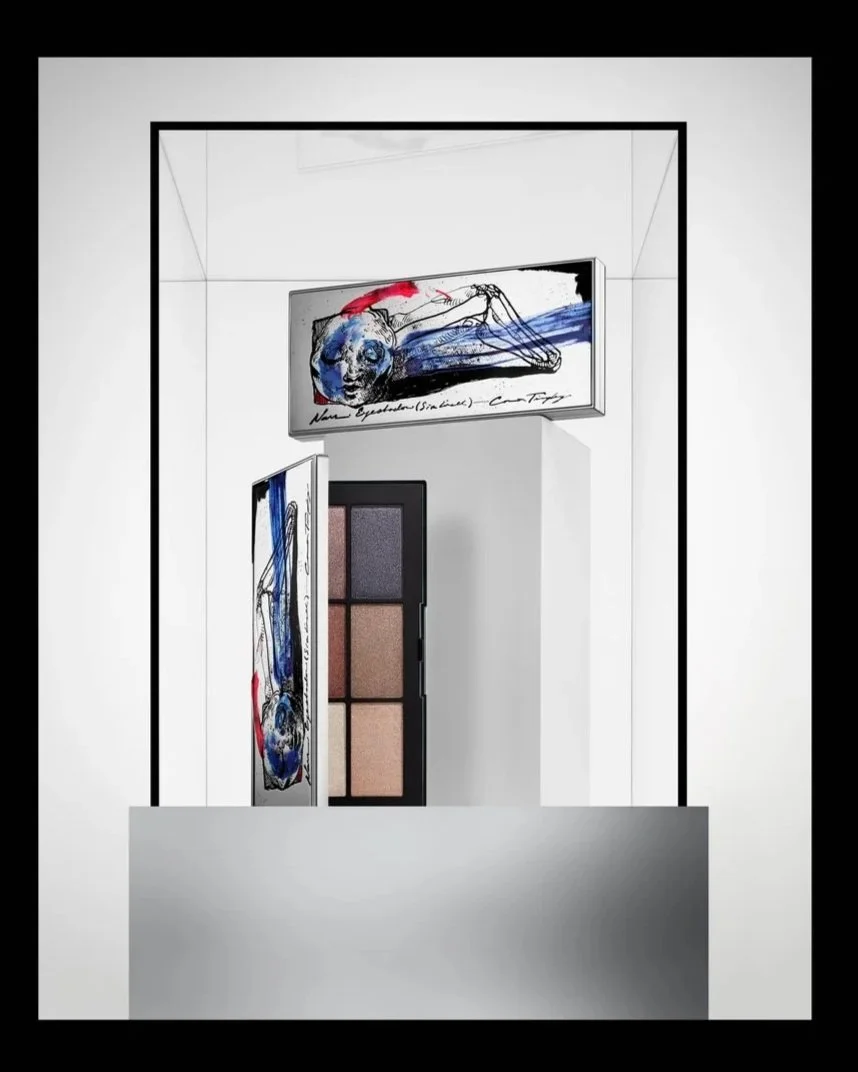 Display of makeup products with art sketches of a human figure and skull, featuring a palette with four shades and decorative panels.