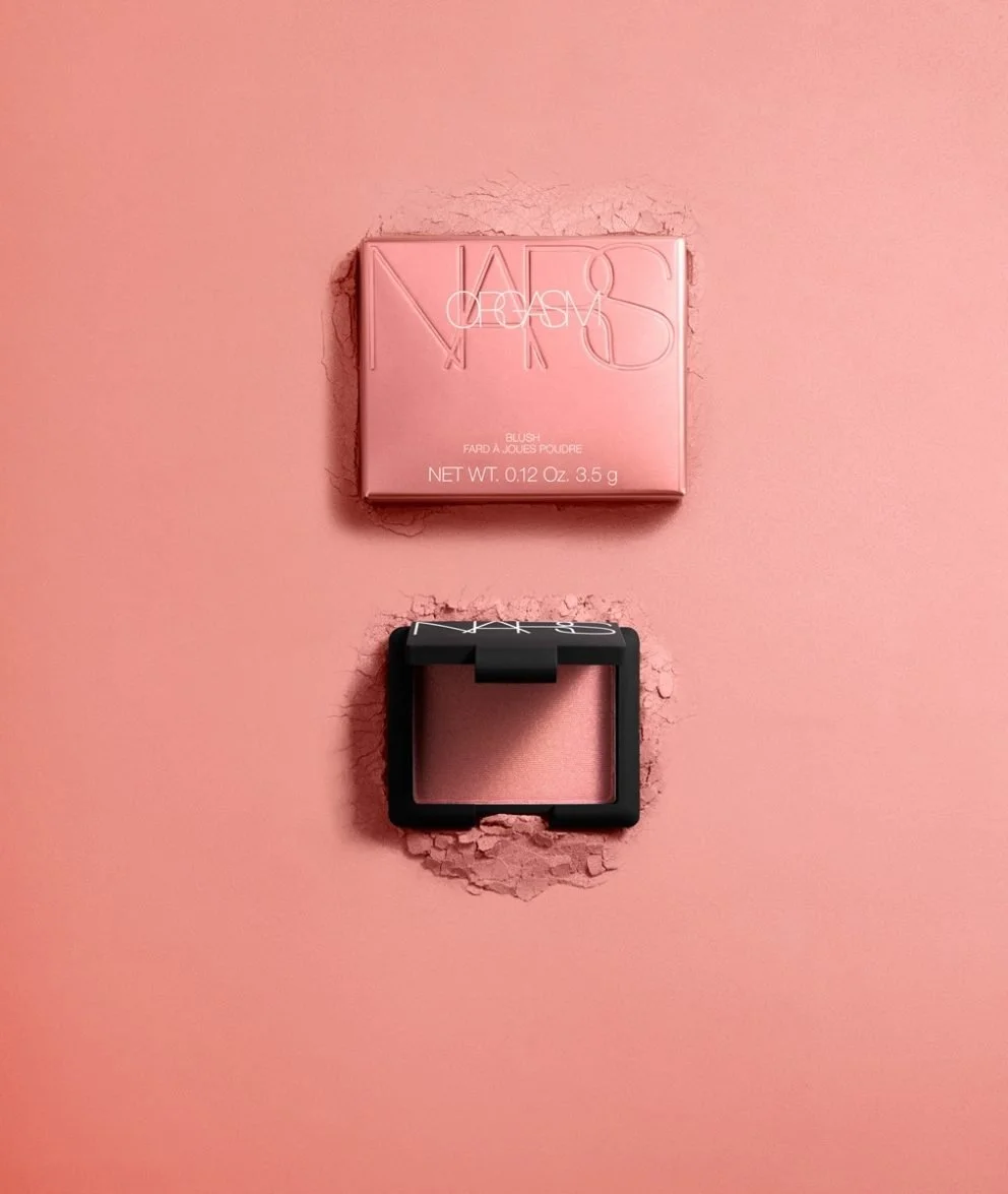 NARS blush compact and its pink packaging on a pink background with a hole in the wall.