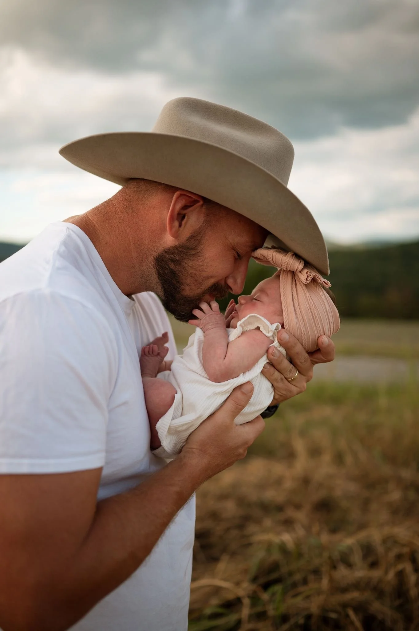 dad snuggling close to baby while she grabs his beard