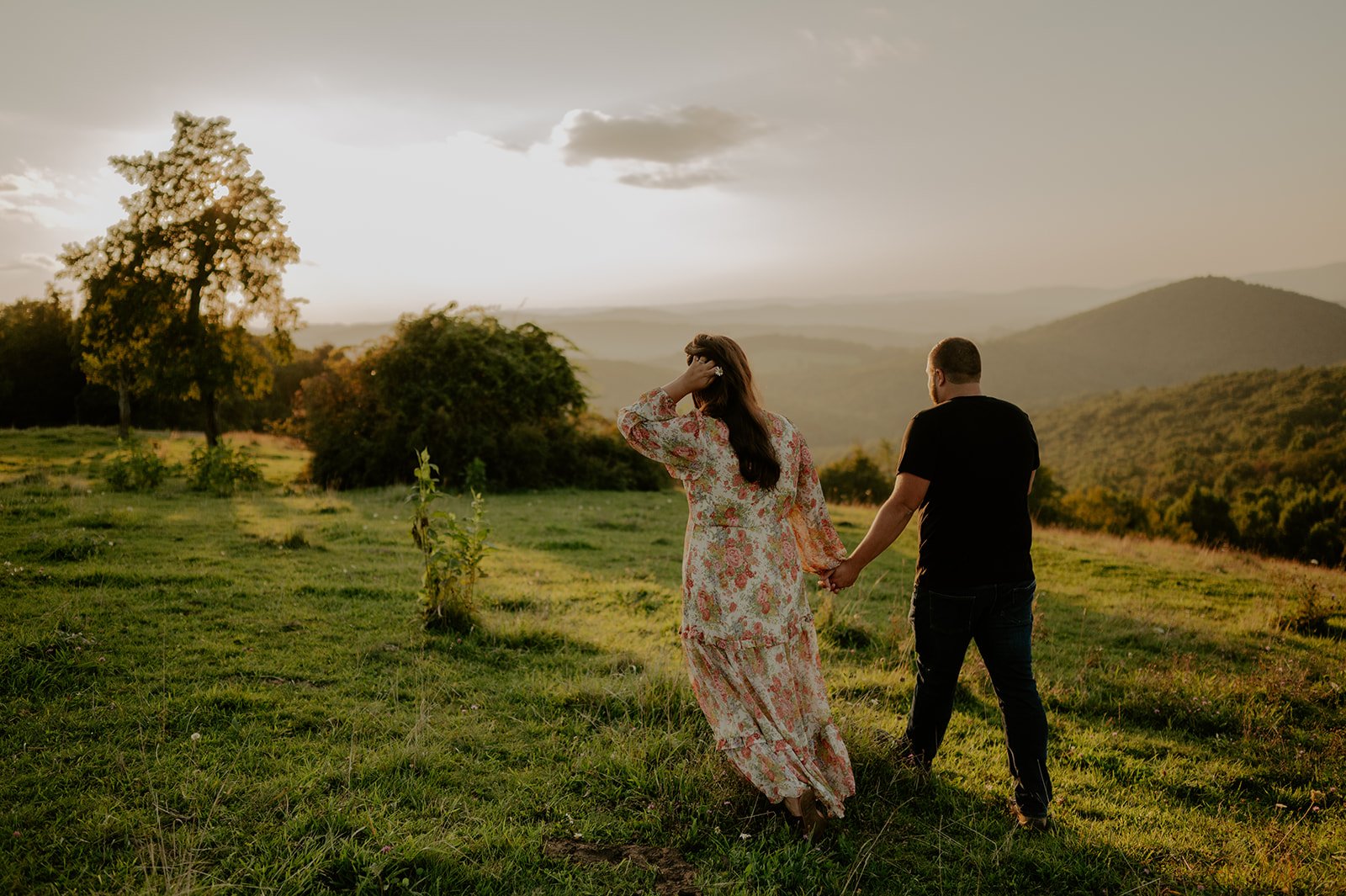 Couple walking away and holding hands with blue ridge mountains in background