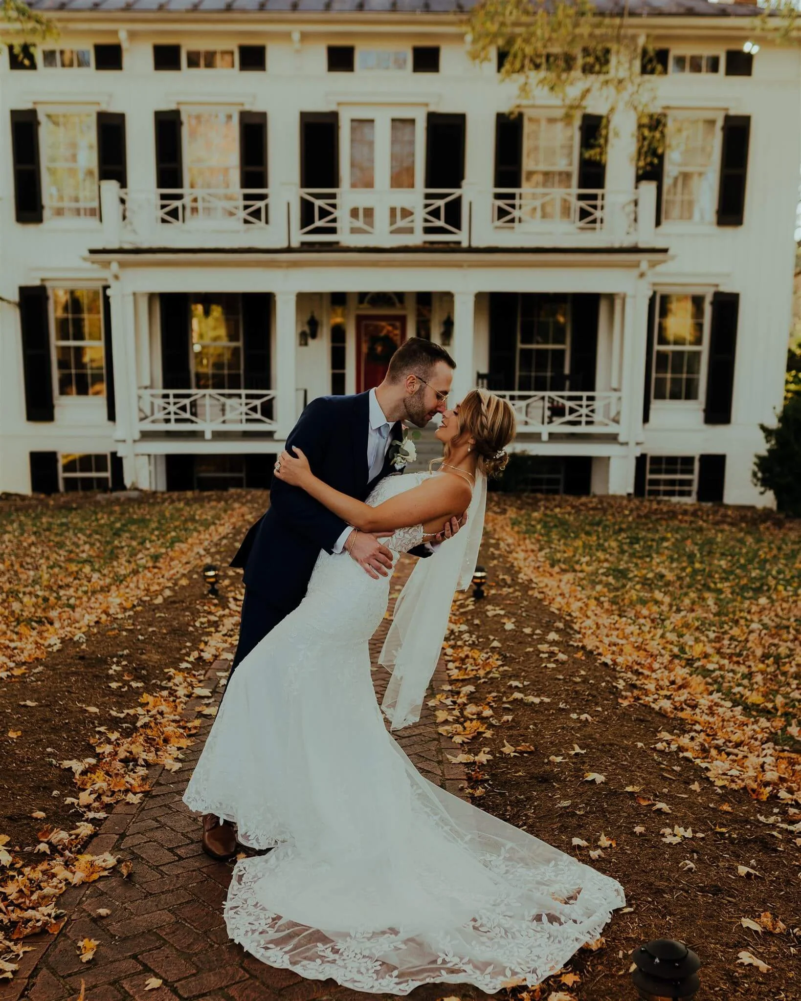 groom dipping bride in front of venue