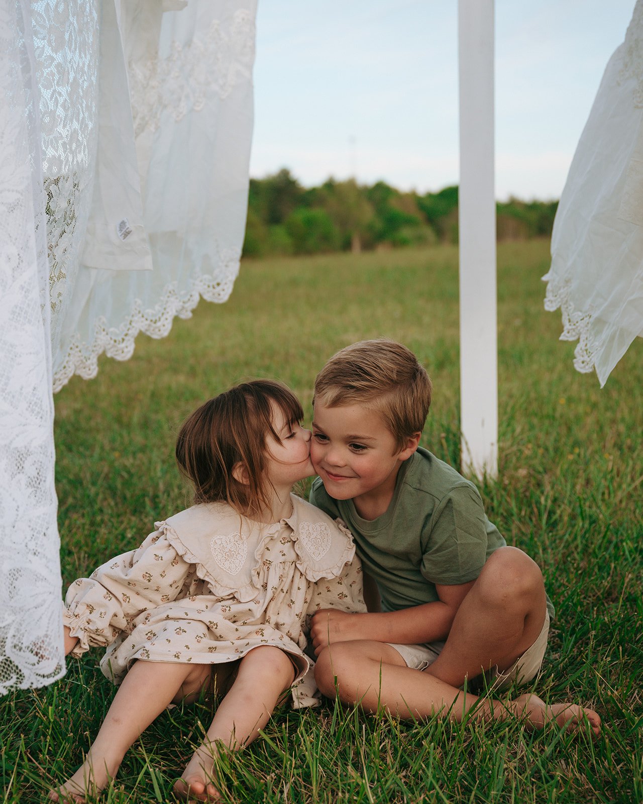 little sister kissing big brother on cheek during family session