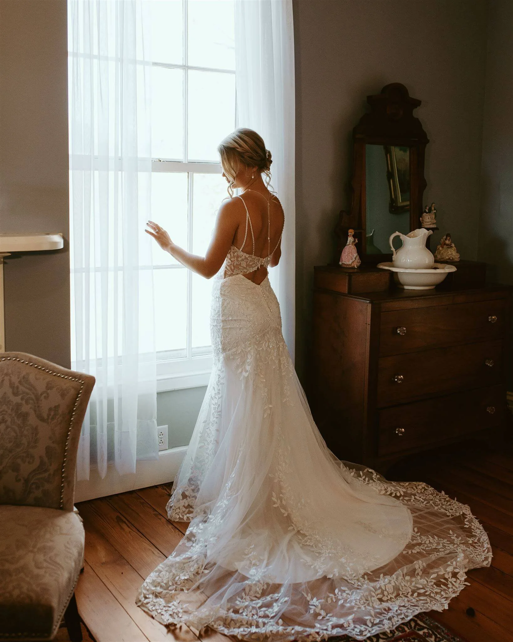 bride looking out window wearing wedding dress